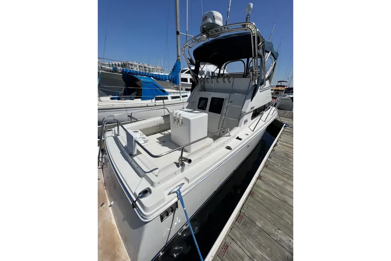 Slide: The Image of 2001 Skipjack 262 Flybridge boat docked at marina, featuring spacious deck and flybridge. - 2