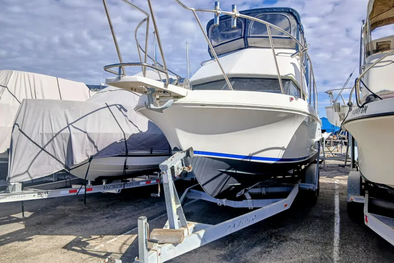 Slide: The Image of 2001 Skipjack 262 Flybridge boat on trailer, parked in marina under cloudy sky. - 8