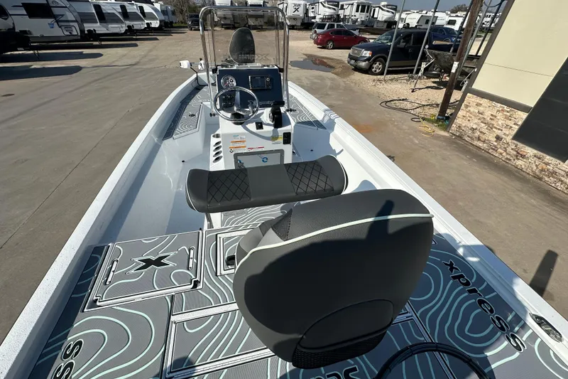 Slide: The Image of 2026 Xpress SW20B boat interior with modern dashboard and seating, parked near RVs. - 14