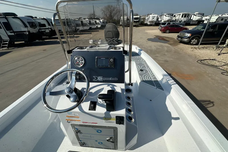 Slide: The Image of 2026 Xpress SW20B boat interior with steering wheel and control panel, parked near RVs. - 15