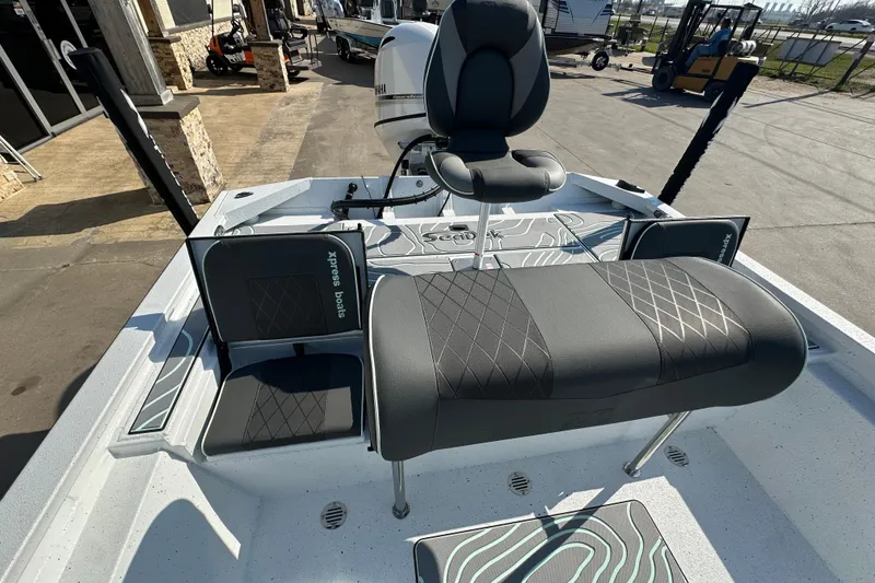 Slide: The Image of 2026 Xpress SW20B boat interior with seating and motor, parked outdoors. - 17