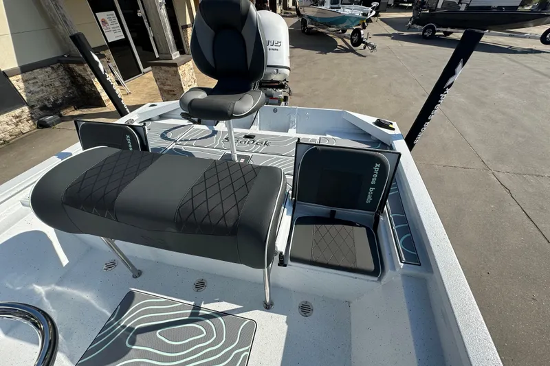 Slide: The Image of 2026 Xpress SW20B boat interior with seating and console, parked outdoors. - 18