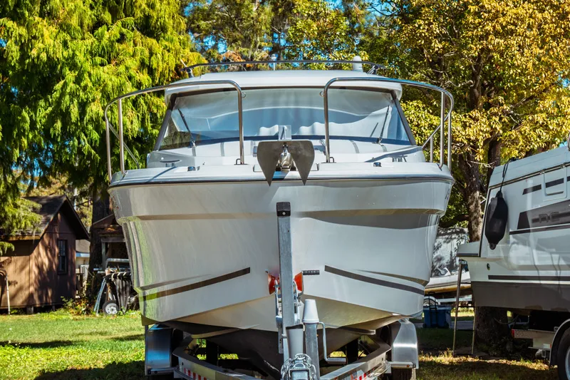 Slide: The Image of 2024 Jeanneau NC 795 Series 2 boat on trailer, surrounded by trees. - 2