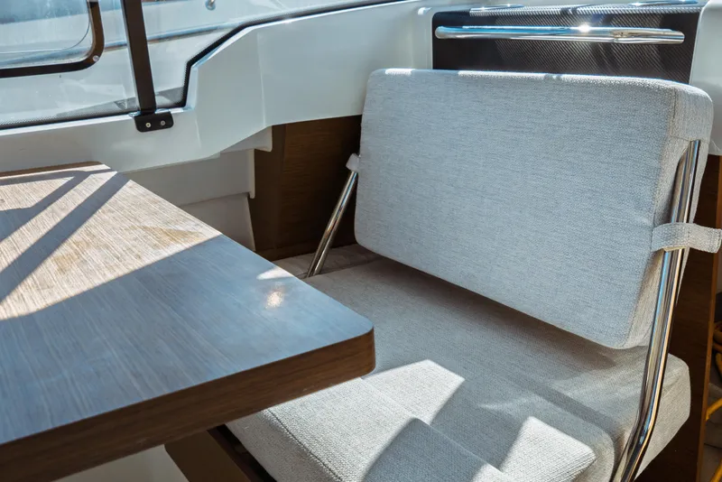 Slide: The Image of 2024 Jeanneau NC 795 Series 2 interior with cushioned seating and wooden table. - 34