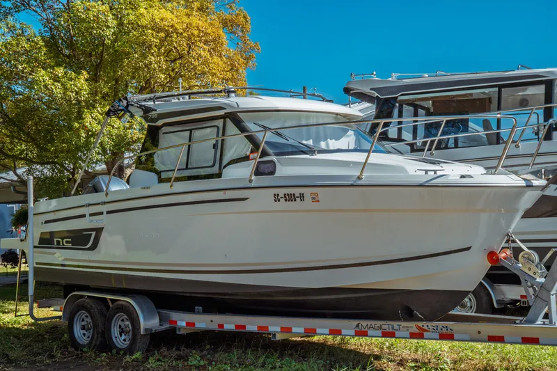 Slide: The Image of 2024 Jeanneau NC 795 Series 2 boat on trailer, surrounded by trees. - 4