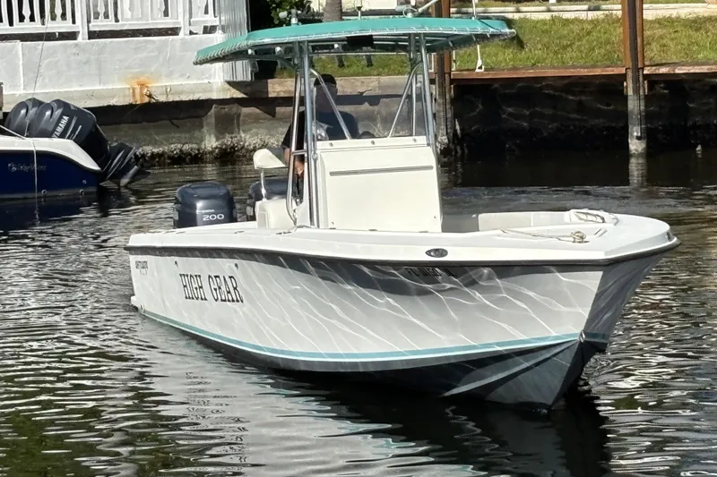 Slide: The Image of 1995 Whitewater 28 boat named "High Gear" on calm water near a dock. - 3