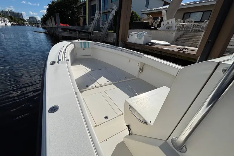 Slide: The Image of 1995 Whitewater 28 boat docked by waterfront homes, showcasing spacious deck and seating area. - 6