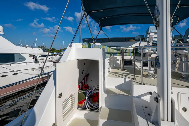 Slide: The Image of 2006 Krogen 58 yacht deck with open storage, striped seating, and marina view. - 49