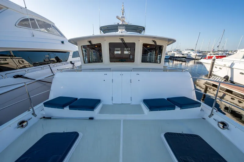 Slide: The Image of 2006 Krogen 58 yacht deck with seating, docked at marina under clear blue sky. - 53