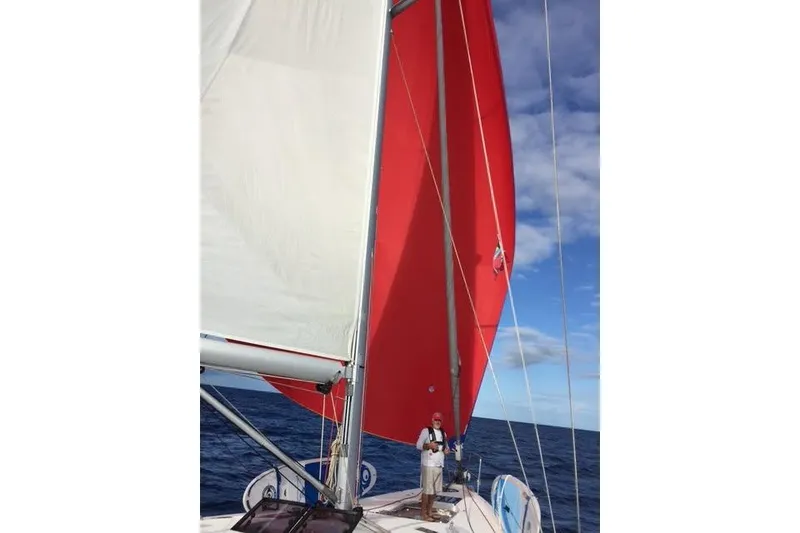 Slide: The Image of 2016 Jeanneau 54 sailboat with red sail on open sea under blue sky. - 46