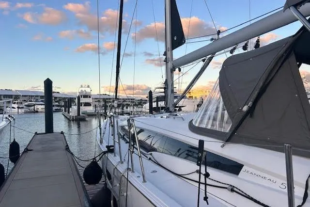 Slide: The Image of 2016 Jeanneau 54 sailboat docked at a marina under a partly cloudy sky. - 6