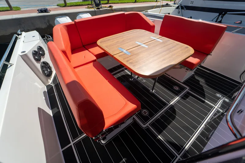 Slide: The Image of Nimbus T11 2022: Red seating area with wooden table on boat. - 14