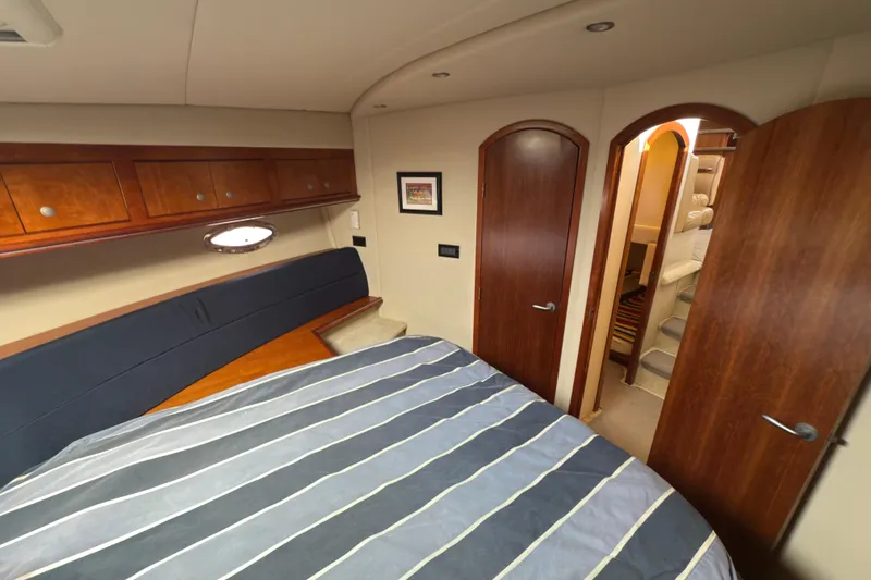 Slide: The Image of Luxurious 2008 Cruisers 455 Motor Yacht bedroom with striped bedding and wooden cabinetry. - 22