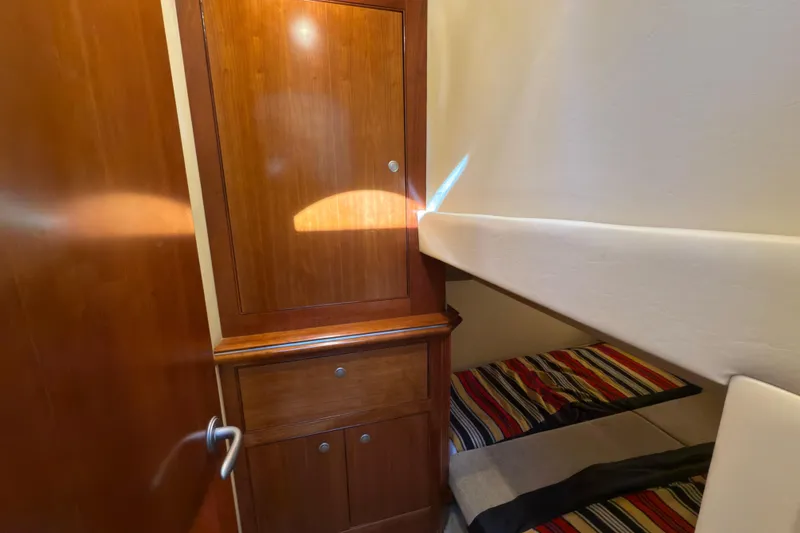 Slide: The Image of Interior of 2008 Cruisers 455 Motor Yacht with wooden cabinetry and striped bedding. - 27