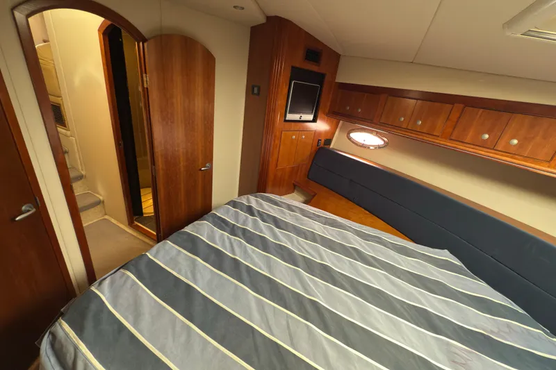 Slide: The Image of Luxurious 2008 Cruisers 455 Motor Yacht bedroom with wood accents and striped bedding. - 23