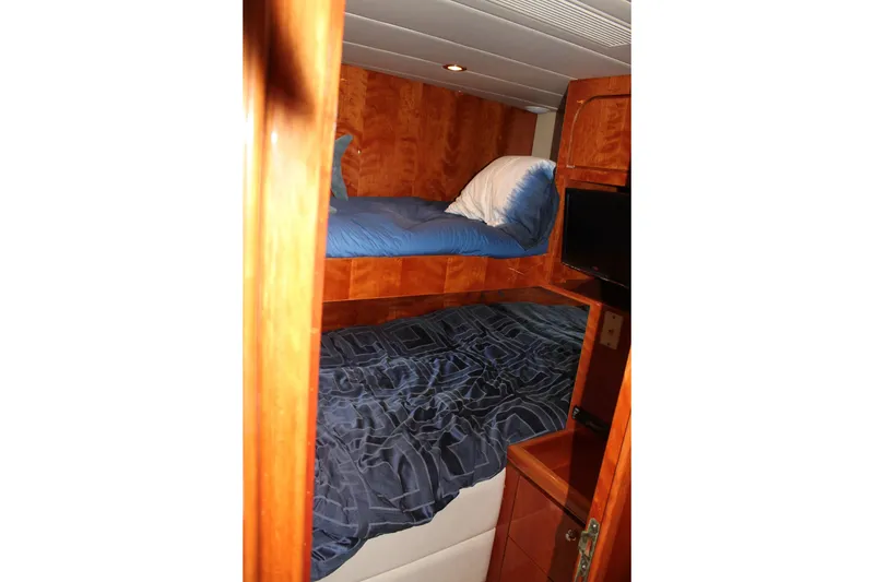 Slide: The Image of Bunk beds in 1999 Horizon 70 Motor Yacht cabin with wood paneling and blue bedding. - 54
