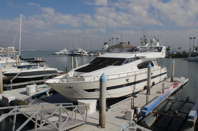 Slide: The Image of 1999 Horizon 70 Motor Yacht docked at a marina under a partly cloudy sky. - 68