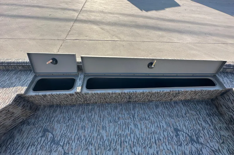 Slide: The Image of 2026 Xpress X18DB boat storage compartments with open lids on patterned deck. - 15