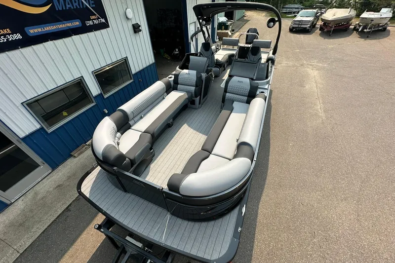 Slide: The Image of 2025 Avalon Excalibur LTD Quad Lounge Windshield boat with spacious seating at a marina. - 9