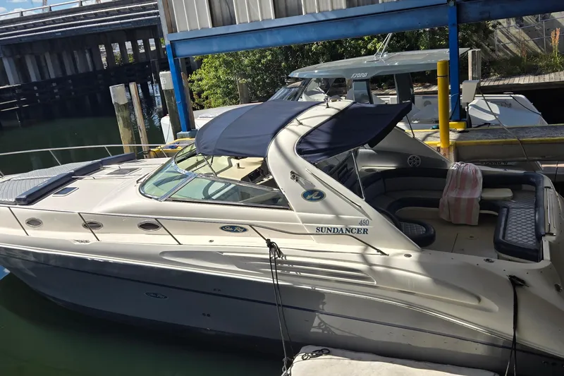 The Image of 1998 Sea Ray 420 Sundancer yacht docked in a marina under a blue canopy. - 1