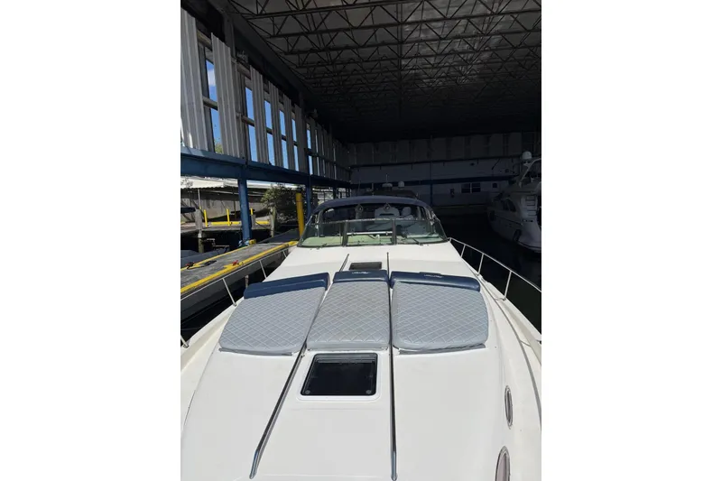 Slide: The Image of 1998 Sea Ray 420 Sundancer yacht in a marina, featuring sun pads on the deck. - 10