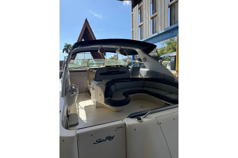 Slide: The Image of 1998 Sea Ray 420 Sundancer boat interior with seating and helm, docked under clear sky. - 9