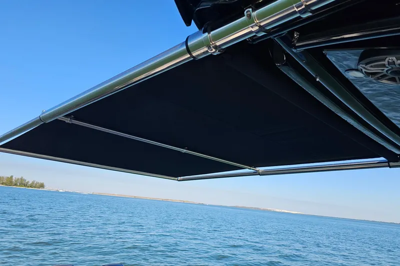 Slide: The Image of 2025 Nor-Tech 390 Sport Center Console with extended sunshade over calm waters. - 15