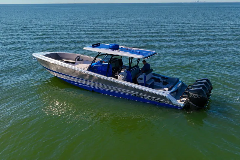 Slide: The Image of 2025 Nor-Tech 390 Sport Center Console boat on calm water, featuring triple outboard engines. - 4