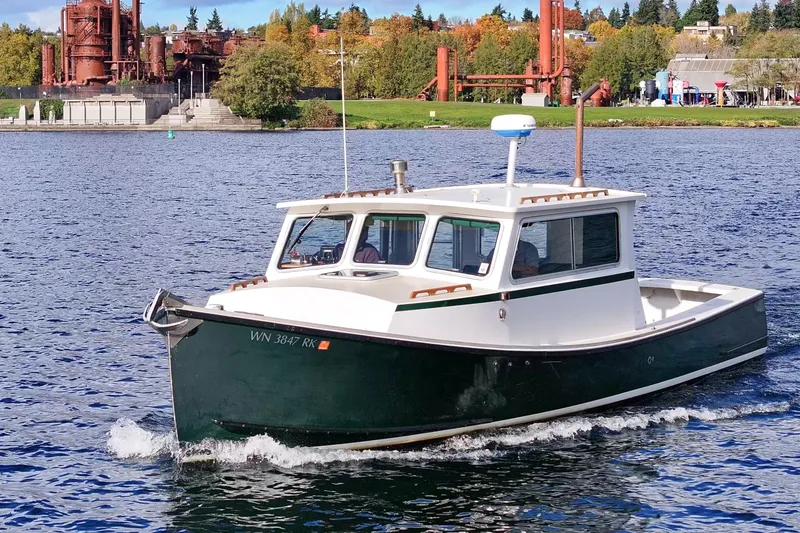 Slide: The Image of 1984 Martin Yachts Lobster Boat cruising on a scenic lake with industrial backdrop. - 1