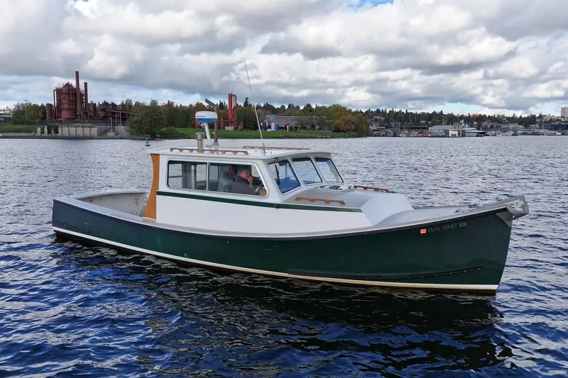 Slide: The Image of 1984 Martin Yachts Lobster Boat on a scenic lake with industrial backdrop. - 12