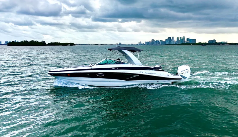 Slide: The Image of 2023 Crownline 285 XS boat on water with skyline backdrop. - 2