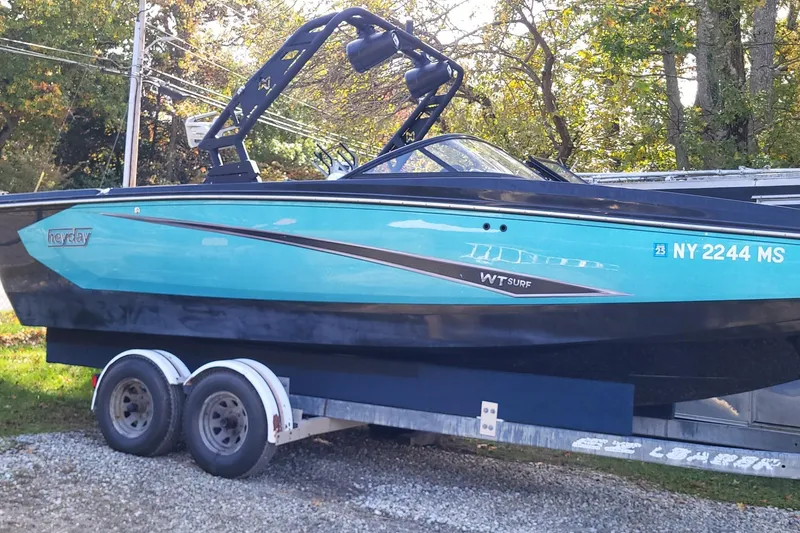 The Image of 2021 Heyday WTSurf boat on trailer, vibrant blue and black design, parked outdoors. - 0