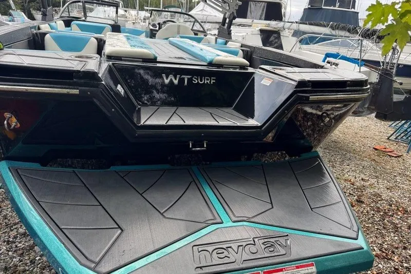 Slide: The Image of 2021 Heyday WTSurf boat with sleek design, docked on gravel surface. - 10