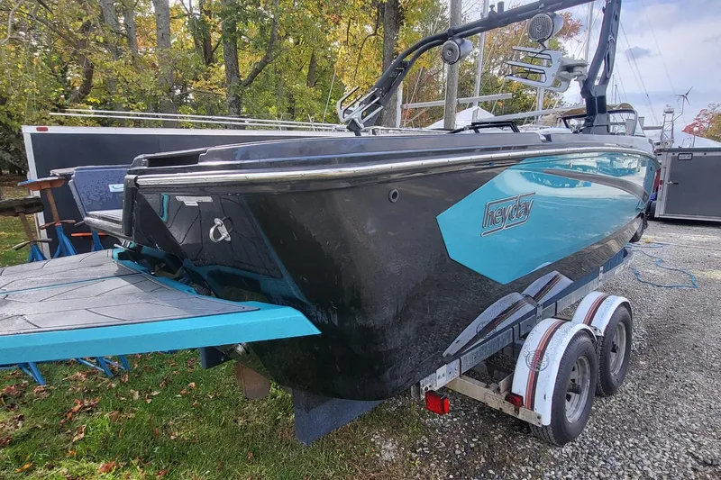 Slide: The Image of 2021 Heyday WTSurf boat on trailer, black and turquoise design, parked outdoors. - 2
