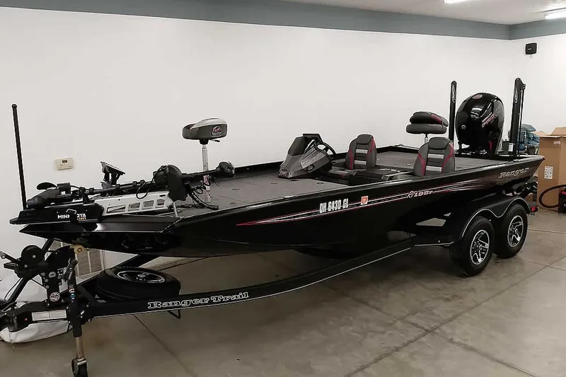 The Image of 2023 Ranger RT198P bass boat in a garage, featuring dual seats and a trolling motor. - 1