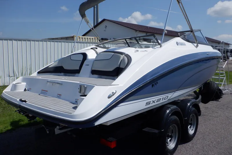 Slide: The Image of 2019 Yamaha SX210 boat on trailer, white and blue design, parked outdoors. - 4