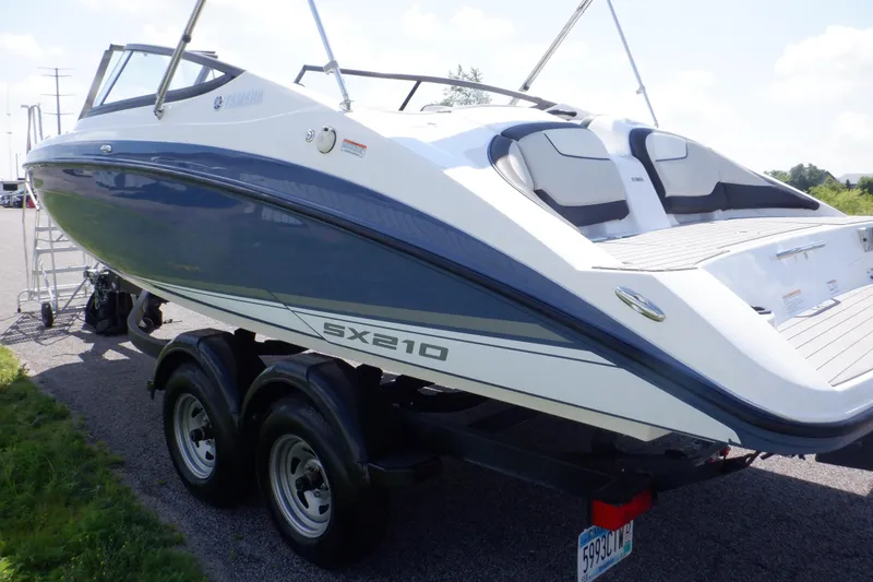 Slide: The Image of 2019 Yamaha SX210 boat on trailer, blue and white design, parked outdoors. - 6