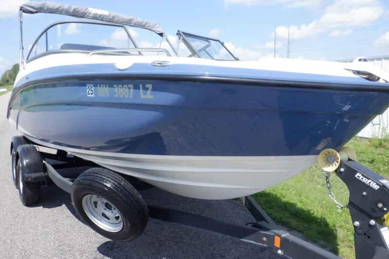 Slide: The Image of 2019 Yamaha Boats SX210 on trailer, blue and white hull, parked outdoors. - 8