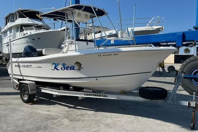 The Image of 2007 Sea Hunt Triton 207 boat on trailer, docked with other vessels in background. - 1