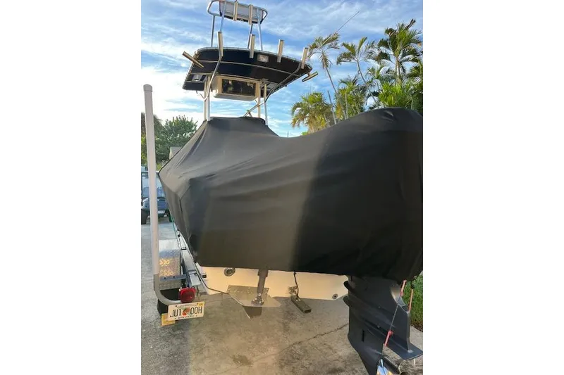 Slide: The Image of 2007 Sea Hunt Triton 207 boat covered, parked on trailer, surrounded by palm trees. - 22