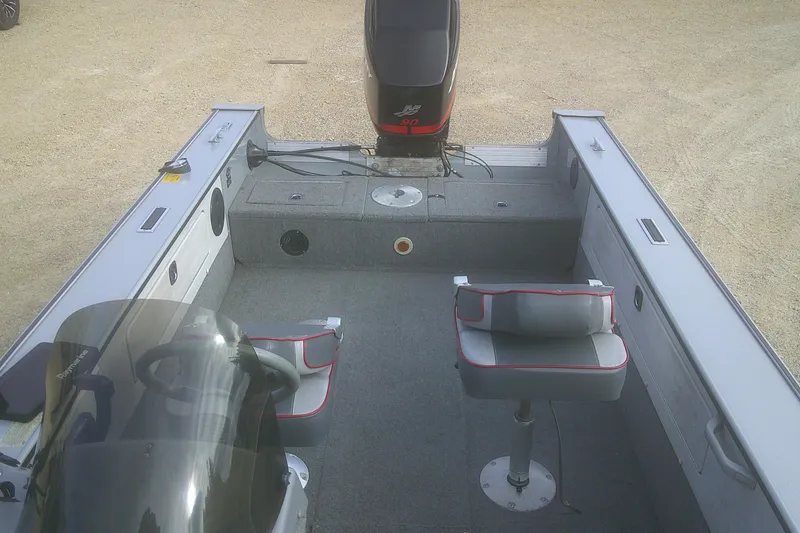 Slide: The Image of 1997 Lund 1660 Pro-V boat interior with seating and motor, on a sandy surface. - 12