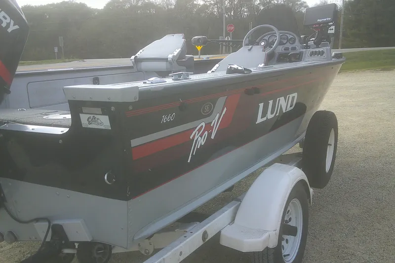 Slide: The Image of 1997 Lund 1660 Pro-V boat on trailer, featuring sleek design and modern equipment. - 24