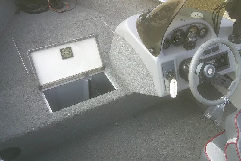 Slide: The Image of 1997 Lund 1660 Pro-V boat interior with steering wheel and open storage compartment. - 5