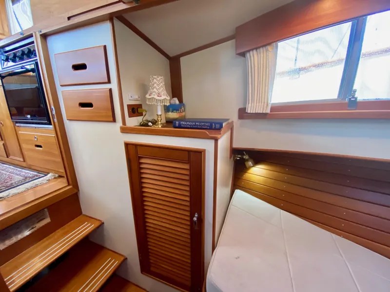 Slide: The Image of 1997 Grand Banks Classic boat cabin with wooden interior and cushioned bed. - 35