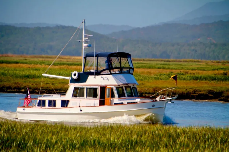Slide: The Image of 1997 Grand Banks Classic yacht on serene water with lush greenery and mountains in the background. - 4