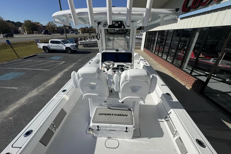 Slide: The Image of 2026 Sportsman Masters 267 Bay Boat interior with white seating and console, parked outdoors. - 17