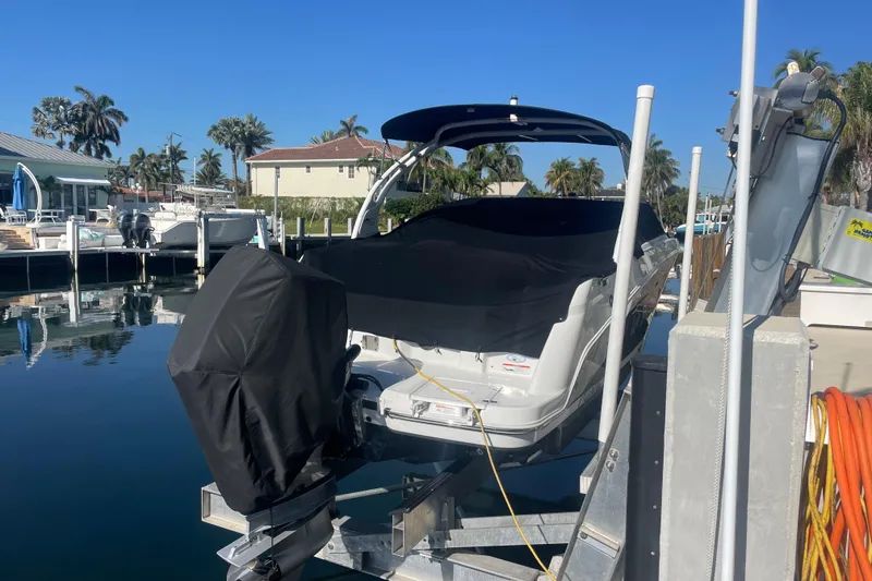 Slide: The Image of 2023 Four Winns HD5 OB boat docked with cover, surrounded by palm trees and clear blue sky. - 5