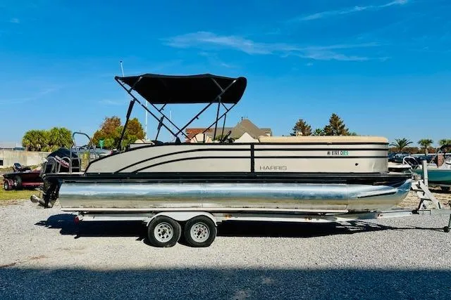 The Image of 2021 Harris 250 Cruiser pontoon boat on trailer under clear blue sky. - 0