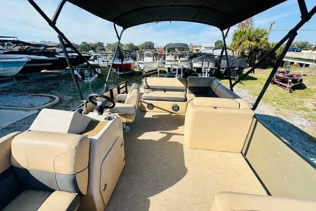 Slide: The Image of 2021 Harris 250 Cruiser pontoon boat with beige seating and canopy, docked outdoors. - 10