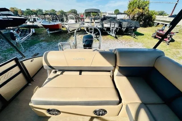 Slide: The Image of 2021 Harris 250 Cruiser pontoon boat with beige seating, parked among other boats. - 11